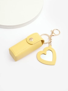 Detail view of yellow PU leather lipstick pouch with heart mirror keychain attachment