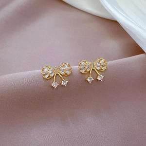 Macro detail of gold butterfly earrings with micro-paved zircons on purple satin fabric