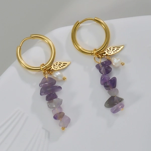 Detail of 14k gold earrings with a wing charm, white pearl, and purple amethyst stone beads