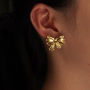Fashionable gold bow-knot stud earrings worn by a model for a refined vintage look