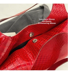 Detail of red crocodile pattern bag featuring glossy finish and metal magnetic closure
