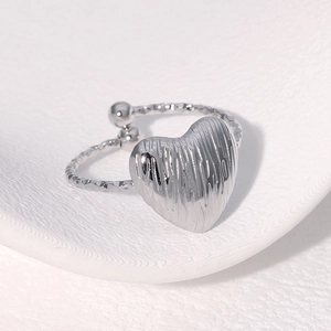 Gros plan détaillé d'une bague coeur argentée avec finition texturée et anneau facetté