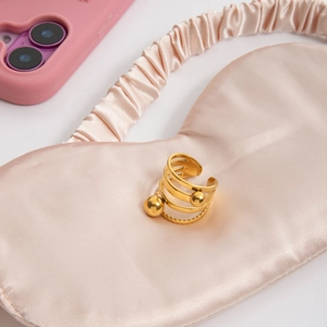 Minimalistischer goldener Mehrschichtring mit Metallkugeln auf Champagner-Seide