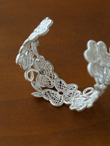 Macro view of detailed silver-plated floral lace hollow pattern on vintage open bangle