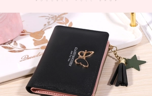 Detail of black bi-fold wallet with gold butterfly buckle, tassel and star pendant charms
