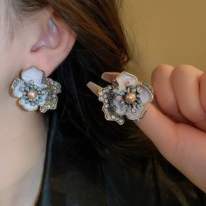 Close-up of vintage flower earrings with pearls and colorful gemstones details