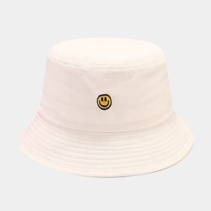 Detailed view of yellow smiley face embroidery on a cream cotton canvas bucket hat