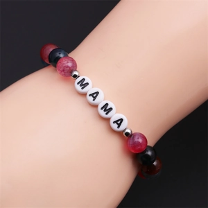 Gros plan d'un bracelet en perles d'agate rouge et noire avec lettres MAMA porté au poignet