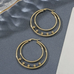Double hoop gold earrings with five small beads on a textured grey background