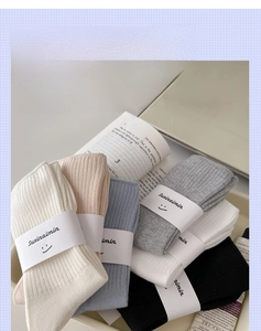 Detail of ribbed knit cotton socks in soft blue and neutral tones with logo packaging
