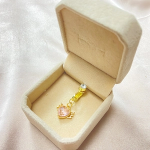 Détail du clip de nombril cœur rose avec ailes dorées dans un coffret en velours