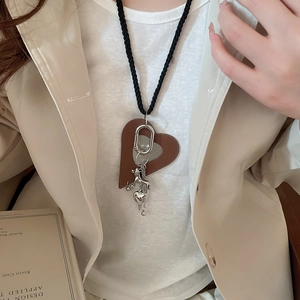 Detail of leather heart and silver horse pendant on black woven cord sweater necklace