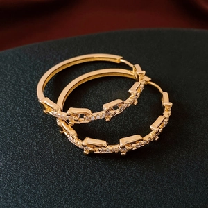 Macro shot of 18K gold plated chain hoop earrings featuring delicate cubic zirconia inlay