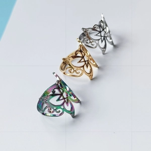 Détail de bagues à nœud celtique en argent, or et multicolore sur un fond quadrillé gris