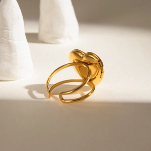 Détail macro d'une bague médaillon coeur dorée avec finition polie et anneau réglable