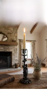Detailed close-up of a vintage black cast iron candlestick holder with aged texture and candle