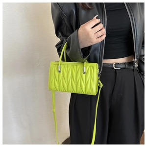 Detailed view of neon green quilted PU leather handbag with shoulder strap on model