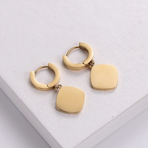 Chic golden square hoop earrings with polished metal finish on white textured stone