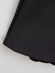 Close-up of the smooth black satin fabric and neat stitching on a camisole dress