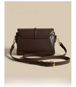 Detail of dark brown leather handbag with vintage buckle and adjustable shoulder strap