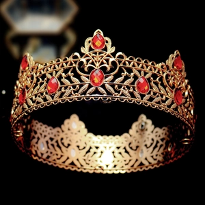 Close-up of golden baroque crown with red oval gemstones and intricate filigree details