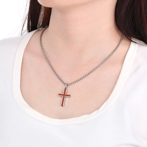 Gros plan du pendentif croix en acier inoxydable avec incrustation de bois de rose