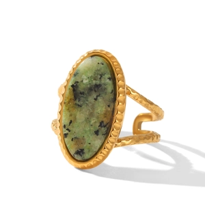 Detail of gold vintage ring featuring a green natural stone with hammered metal texture