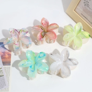Detail view of five marble texture flower hair clips in various gradient colors