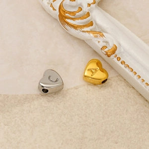Elegant 18K gold and silver heart pendants with letter engravings on textured background