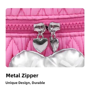 Macro detail of pink quilted makeup bag with silver heart-shaped zippers and charms