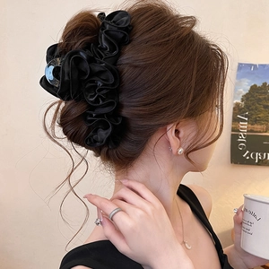 Pince à cheveux élégante en tissu plissé noir portée par un modèle avec un chignon chic