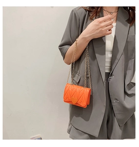 Detail of heart-shaped twist lock and V-shaped pattern on orange silicone chain bag