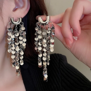 Close-up of silver tassel earrings with round metal sequins worn by a female model
