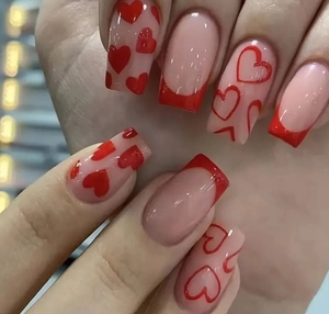 Macro detail of red heart press-on nails with french tip design on nude base