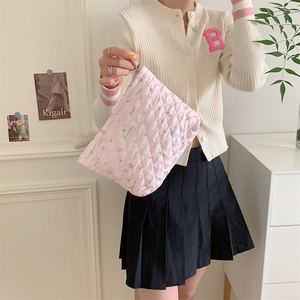 Detailed view of pink quilted fabric makeup bag with floral print and zipper closure