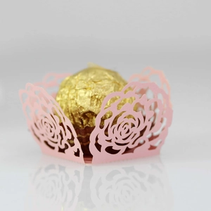 Macro shot of pink laser-cut rose hollow paper chocolate wrapper with gold foil truffle