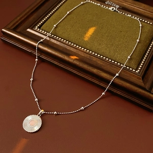 Détail du collier marguerite en argent avec gemme rose sur cadre en bois de style vintage
