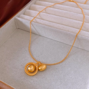 Close-up of matte gold flower necklace with pattern ring and round bead charms