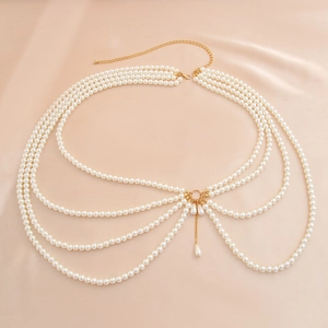 Detail of multilayer pearl body chain with gold metal links on a beige silk background