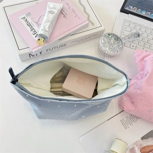 Detail of pink and blue star sequin canvas makeup bags with silver zippers on a desk