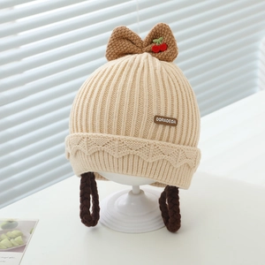 Détail d'un bonnet en tricot pour bébé avec cerises et tresses de perruque brunes