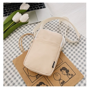 Detail of beige corduroy crossbody bag with Sport tag on a stylish lifestyle background