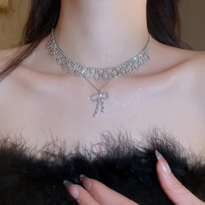 Close-up of sparkling silver bow pendant necklace with hollow lace design on a model