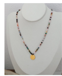 Detail view of colorful beaded necklace with gold Love Angel pendant on display mannequin