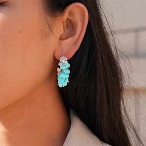Detail of vintage irregular turquoise stone stud earrings with C-shaped silver needle