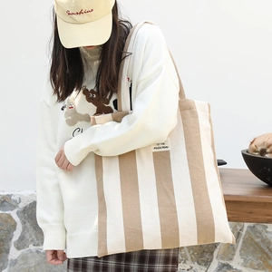 Minimalist knit tote bag with beige vertical stripes shown in a stylish studio setting