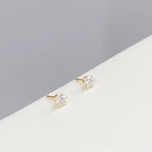 Macro view of gold-plated single stud earring with crystal on beige leather background