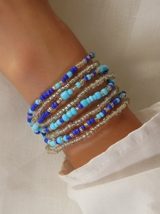 Detailed close-up of multilayered blue and silver glass beaded bracelets on a model's wrist