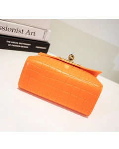 Detail of orange crocodile embossed silicone bag with golden sphere twist lock