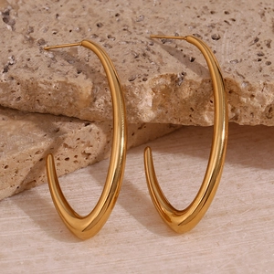 Detailed view of polished gold teardrop metal earrings displayed on natural stone blocks